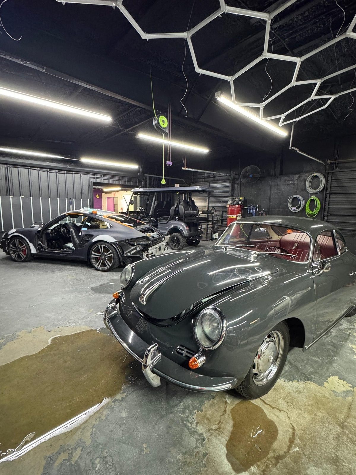 1964 Porsche 356 SC parked in the shop on arrival day, hexagonal lighting overhead