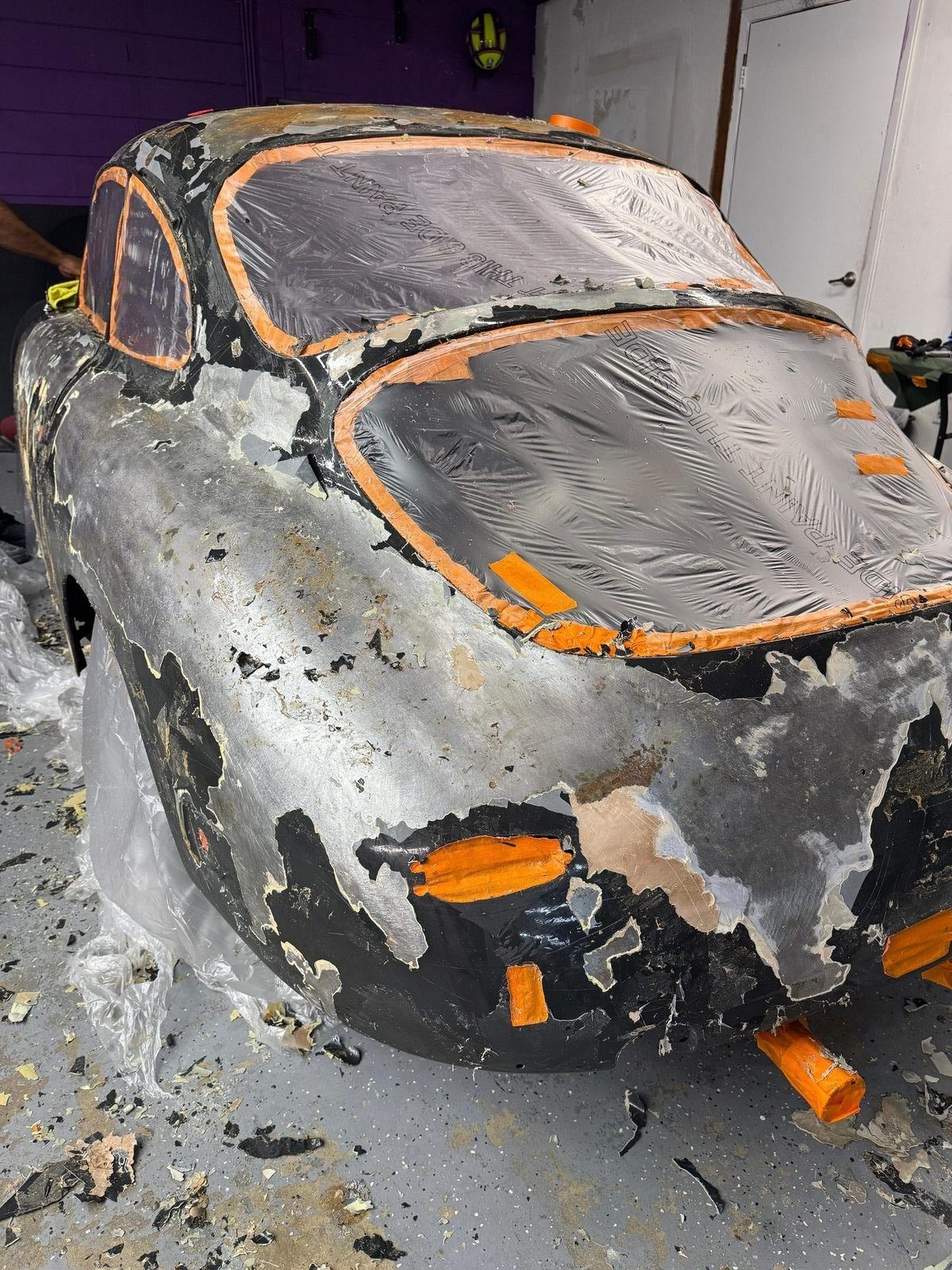 Porsche 356 SC stripped to bare metal — masking and large patches of exposed steel