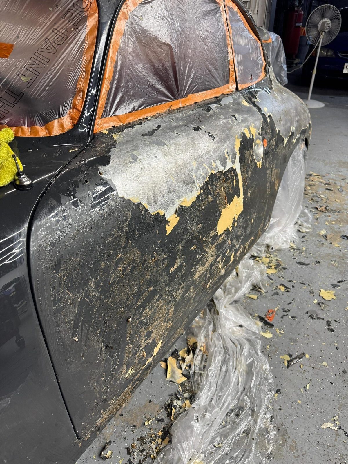 Closeup of the 356 SC rocker panel showing layers of old paint, bondo and bare metal